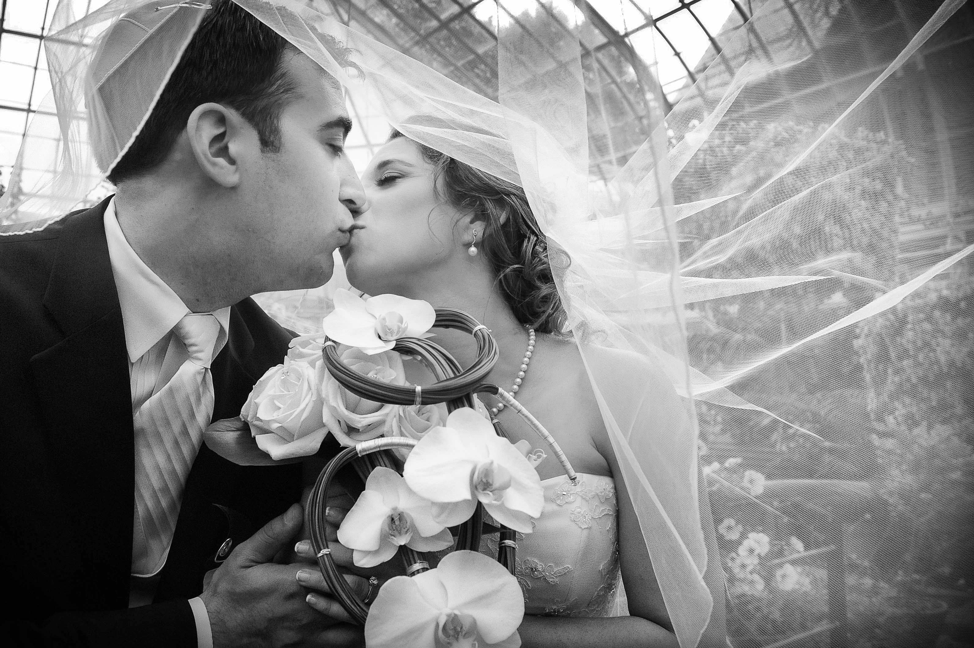 charming wedding couple together romantic kiss under veil with orchids black white photo by lavimage montreal